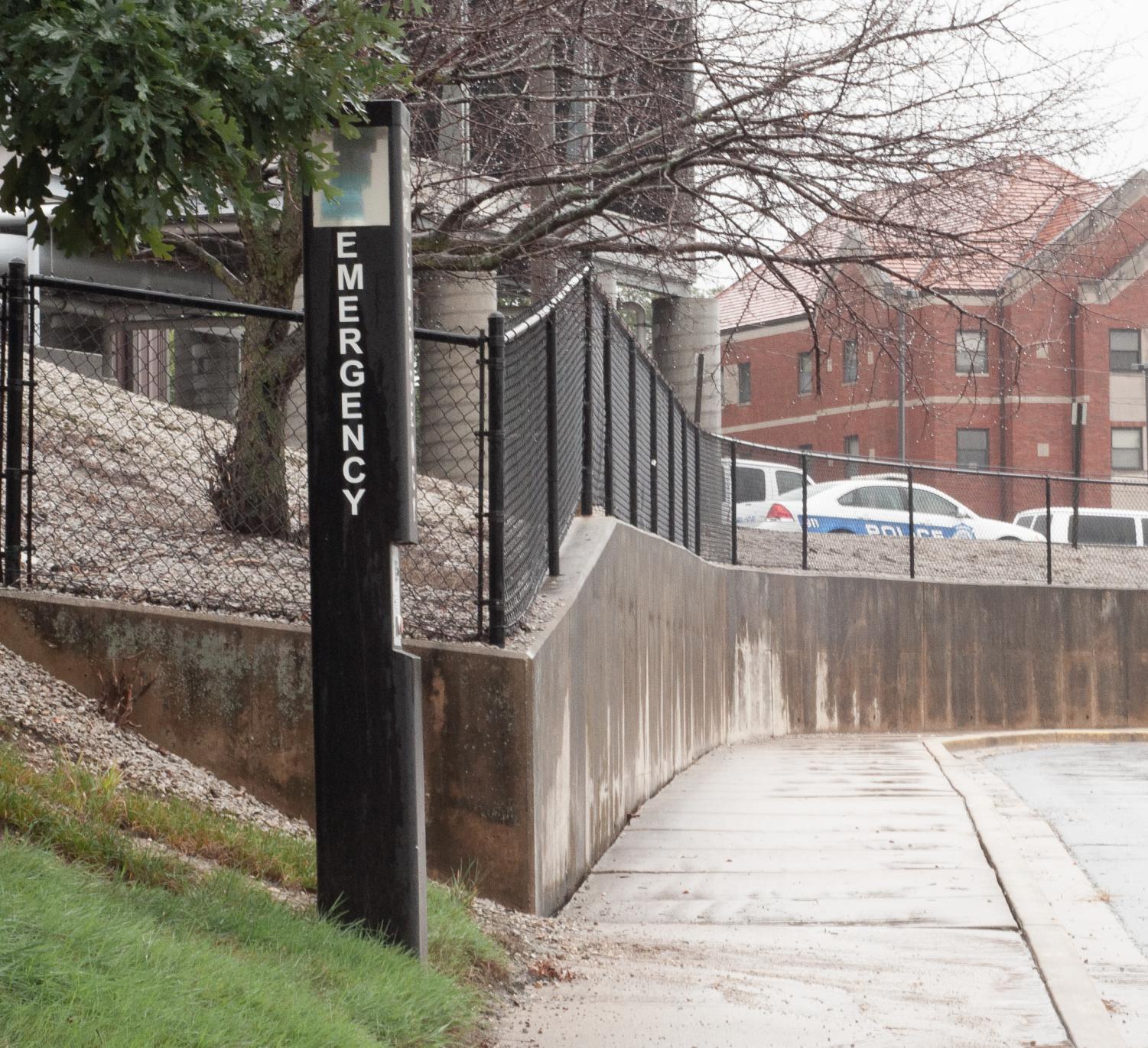 A Safety Phone stands next to the sidewalk on the way to the Freshman lot near Dolson Hall - Where many students walk daily to reach their cars.