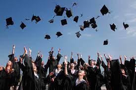 Graduates, dressed in black gowns, throw their hats into the air.