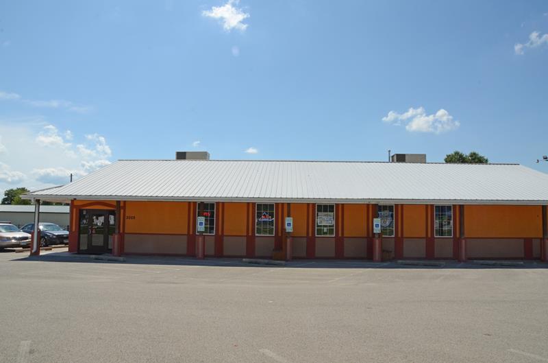 An orange building in a parking lot. There's a blue sky behind the building.