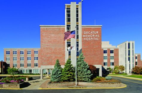 A red brick building with the words Decatur Memorial Hospital on the front. An American flag waves in front of the building.