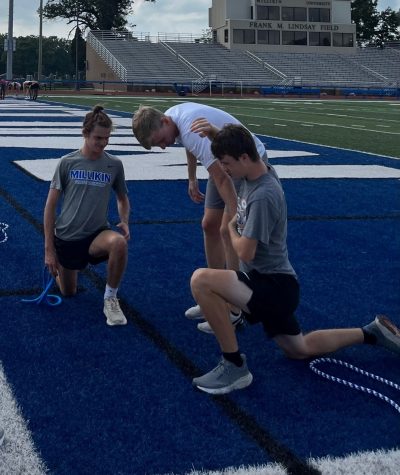 Assistant coach Ben Kuxmann helps lead stretching. Kuxmann was a former standout for the Big Blue and has since decided to join the coaching staff for the 2022 season.